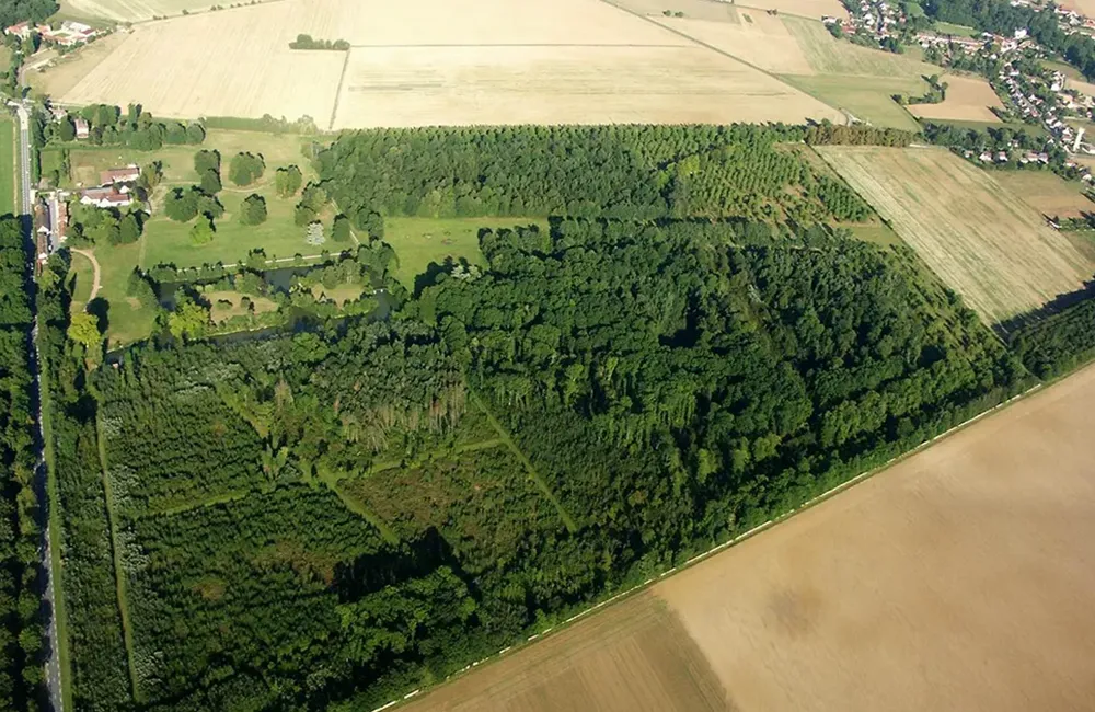 Vue aérienne de Lumigny Safari Reserve, avec de grands espaces boisés, des prairies et des champs environnants.