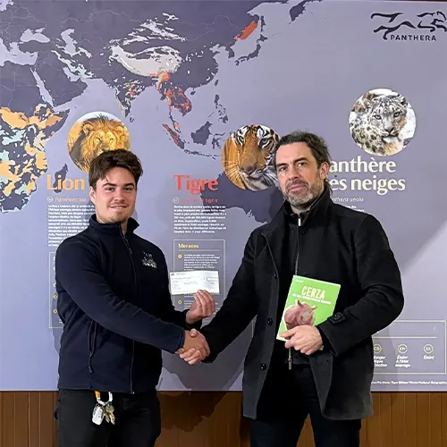 Hugo Jardin Président Lumigny Safari Reserve et Grégory Breton Directeur Panthera se serrant la main devant un panneau de présentation sur les grands félins.